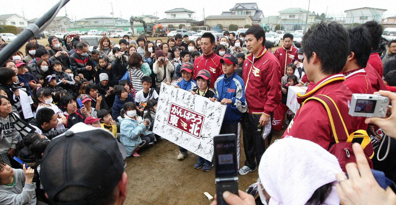 11年4月、東松島市立大曲小学校を訪れメッセージボードを渡した嶋と田中