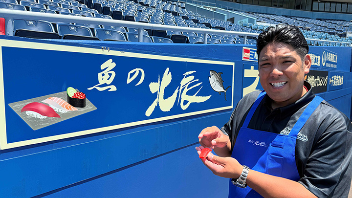 【一日店長「ごっちゃし!」】きょうのパ・リーグ【6月25日】 – パ・リーグ.com ZOZOマリンスタジアムに設置されている「魚の北辰」広告と井上晴哉さん【写真:球団提供】