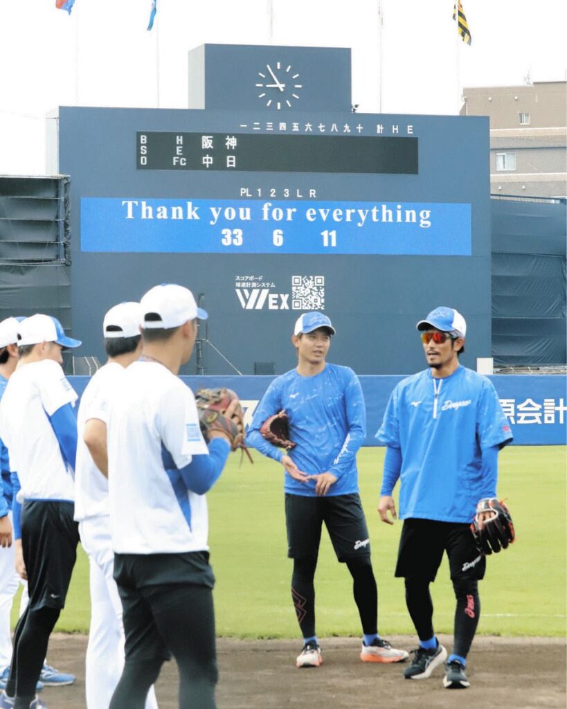 引退する３選手への感謝のメッセージが掲出された電光掲示板の前で試合前練習に臨む祖父江（右）、岡田（中央）