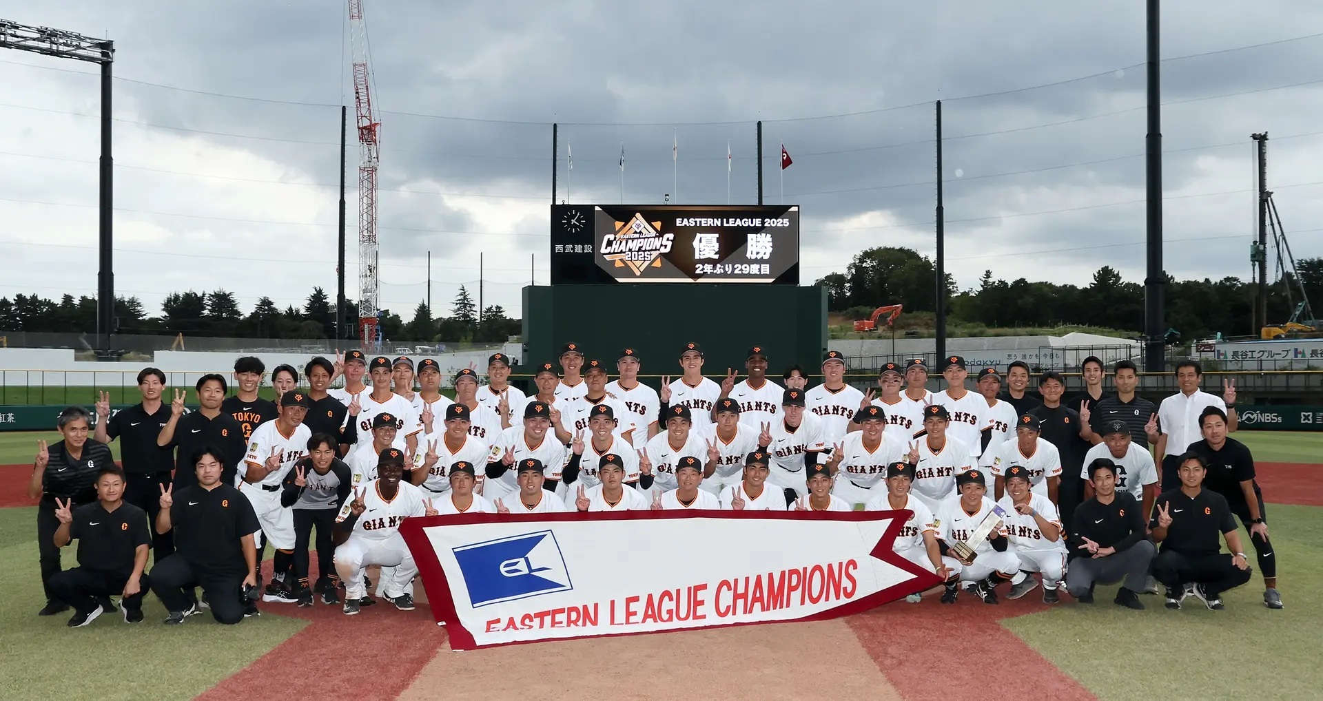 優勝ペナントを広げて『ファーム日本選手権』優勝を誓うジャイアンツの選手と関係者 ※読売巨人軍公式サイトより