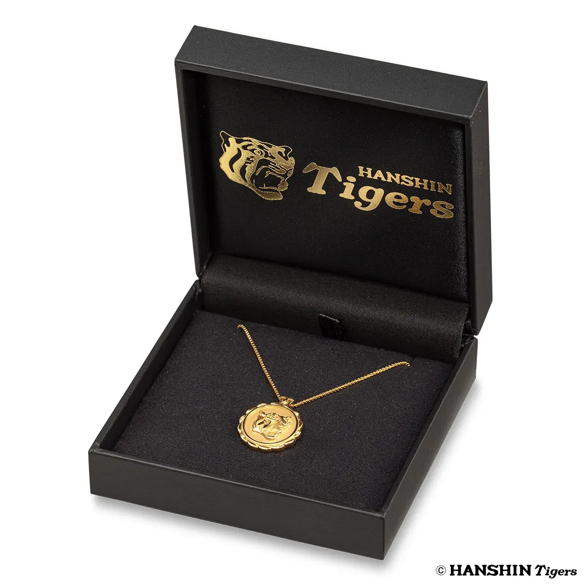 阪神タイガースのロゴが入った金のネックレスが、黒い箱に入っている写真です。
